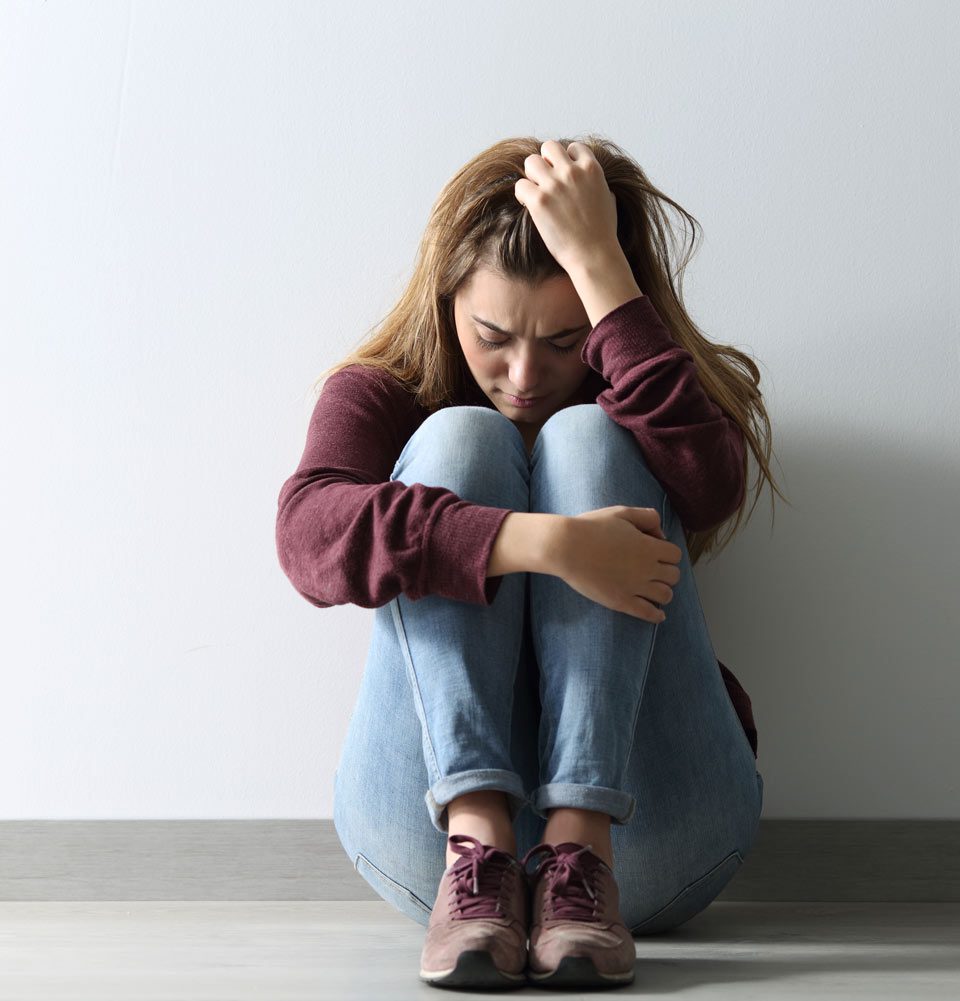 sad young woman hugging knees to chest