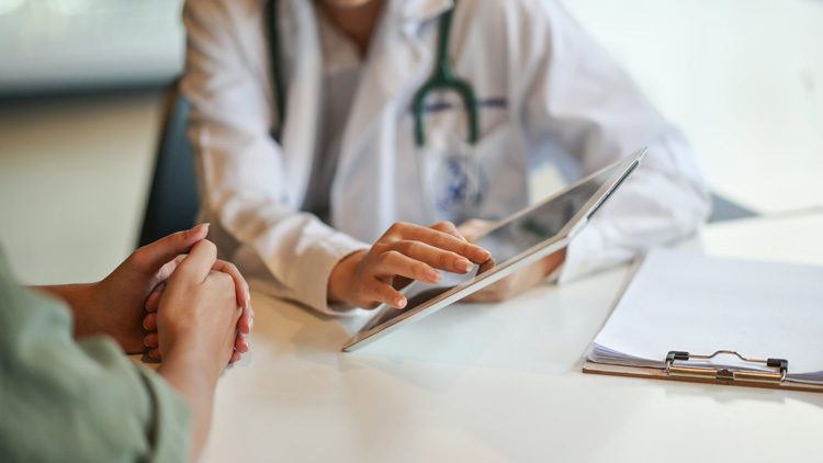 person talking with doctor - doctor showing patient something on tablet computer - chronic pain