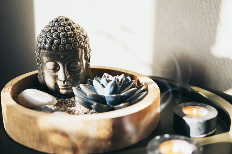 planter with small Buddha head and succulent next to candles - mindfulness