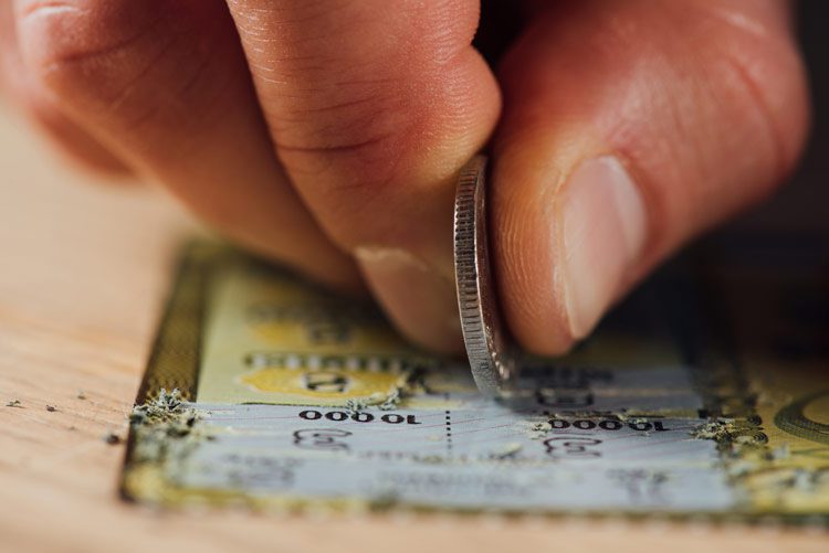 Substitute Addiction, closeup of hand using coin to scratch a scratch off lottery ticket - substitute addiction