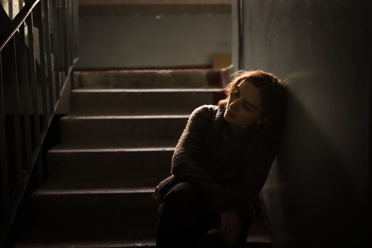 defeated looking woman sitting on stairs - rock bottom